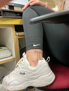 a woman sitting in a chair with her foot up on the computer desk and wearing white sneakers