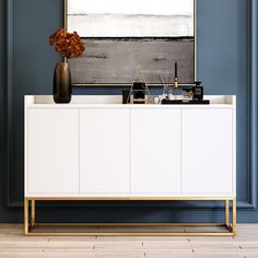 a white and gold sideboard in a blue room with a painting on the wall