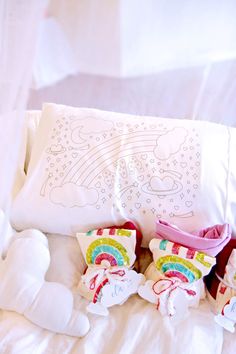 two teddy bears are laying on a bed next to a pillow with a rainbow design