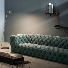 a blue couch sitting next to a lamp on a table in front of a wall