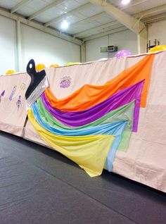 a large rainbow colored banner on top of a black floor in an indoor gym area