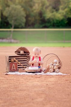 a baby sitting on top of a baseball field holding a racquet and ball