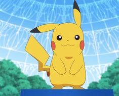 a pikachu sitting on top of a blue box in front of some trees