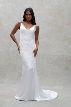 a woman in a white wedding dress posing for the camera with her hands on her hips