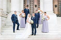 a bride and groom with their bridal party in front of the doors of a building