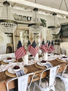 a dining room table with american flags on it and place settings in front of the chandelier