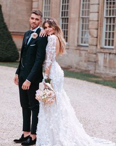 a man and woman standing next to each other in front of a building