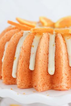 a bundt cake with icing and orange wedges on a white platter