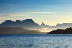 the sun shines on some mountains in the distance as it reflects off the water