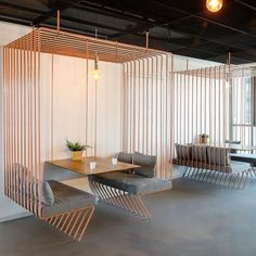 an office space with chairs and tables in the center, hanging from metal rods on the ceiling