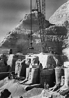 an old black and white photo of a construction site in front of a large mountain