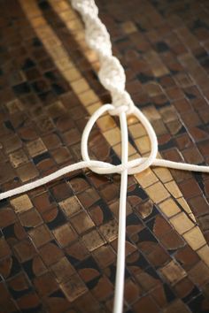 a close up of a cross on a tile floor with a knot in the middle