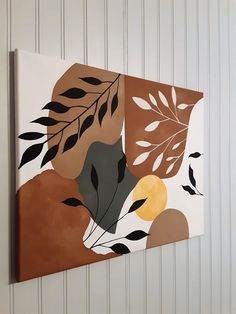 a painting hanging on the side of a wall with leaves and circles painted on it