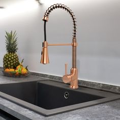 a kitchen sink with a copper faucet next to a pineapple