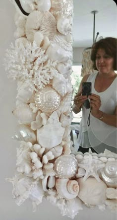 a woman is taking a photo of some sea shells and corals on the wall