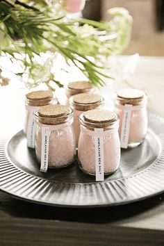 small jars filled with pink sand sit on a plate