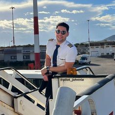 a man wearing sunglasses and a tie standing on the deck of a boat with his arms crossed