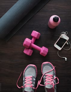 a pair of pink shoes and dumbs next to a cell phone