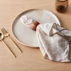 a white plate topped with an onion on top of a wooden table next to utensils