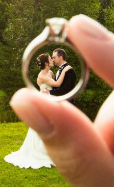 a bride and groom holding their wedding ring in front of the photographer's face