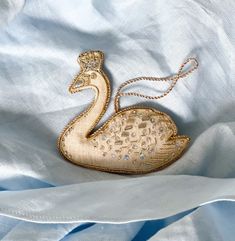 a gold swan brooch sitting on top of a white cloth