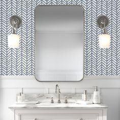 a bathroom vanity with two sinks and a large mirror above it, in front of a chevron wallpapered pattern