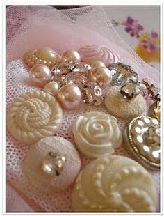 several different types of buttons are laying on a piece of cloth with pink flowers in the background