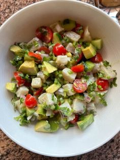 a white bowl filled with chopped vegetables on top of a table next to utensils