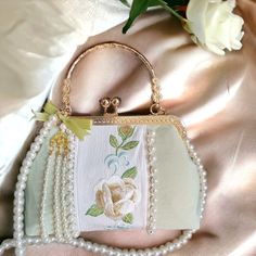 ⭐️ Introducing our flower silk embroidered top handle crossbody bag that's so beautiful to keep for yourself or gift to your loved ones. ⭐️ The bag comes with pearl strap that's easy to carry and to style. ⭐️ The designs are so unique that you could hardly find it anywhere else. 🌸 Double Side Flowers Style: This style has a clean mint green primary color with lines of pearl beads on the bag. The design features elegant white peonies on one side, and green bamboo forest on the other. The dangly charm that's designed for this style is assembled with pearl beaded tassels. 🌸 Waterlily Embroidery Style: This style is so carefully embroidered with lots of pink lotus flowers that are so vivid and delicate. There is a baroque style pearl right in the center of the bag. The dangly charm that's de Portable Top Handle Shoulder Bag For Gift, Evening Bag With Detachable Top Handle, Handheld Shoulder Bag With Pearl Handle For Gift, Evening Bag With Detachable Top Handle For Gifts, Handheld Bags As Gifts, Portable Handheld Bags For Gifts, Handheld Portable Bags As Gifts, White Shoulder Bag With Detachable Handle As Gift, Top Handle Mobile Phone Bag As Gift