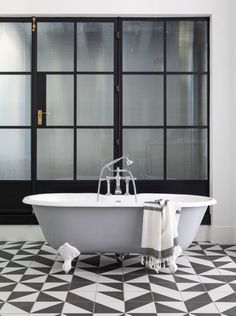 an old fashioned claw foot bathtub sits in the middle of a black and white tiled floor