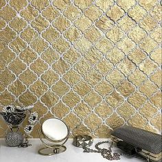 gold wallpaper with white and silver accents on it's surface, next to other decorative items