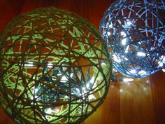 two decorative balls are sitting on a table with string lights in them and one is lit up