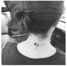 a woman's back neck with a dandelion tattoo