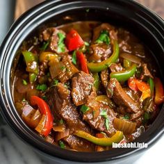 a bowl filled with beef and peppers on top of a table