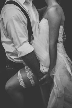 black and white photograph of a bride and groom kissing each other in front of a dark background