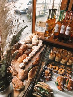 an assortment of breads and pastries on display in front of a store window