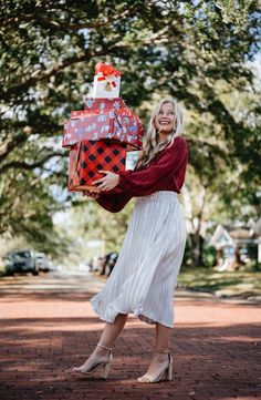 a woman in a white dress is holding a gift box and smiling at the camera