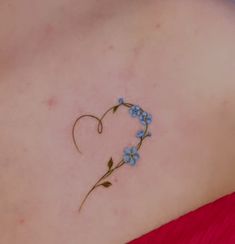 a small blue flower tattoo on the back of a woman's shoulder and chest