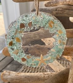 a sea glass ornament hanging from a rope on a wooden chair with seashells and starfish