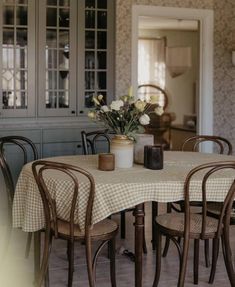 a dining room table with chairs and a vase filled with flowers