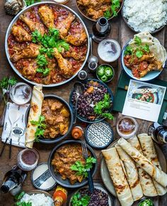 an overhead view of food and drinks on a wooden table, including pita breads