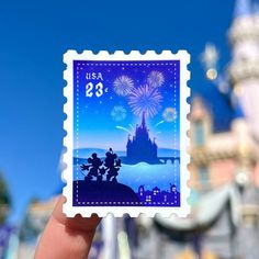 someone is holding up a stamp with a castle in the background