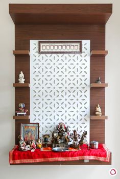 a shelf with many items on it in front of a white wall and red table cloth