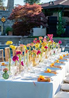 a long table is set with flowers in vases and place settings for the guests