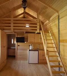 a kitchen and stairs in a small wooden cabin with wood flooring on the walls