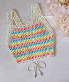 a crocheted baby bib with a bow on the side and flowers in the background