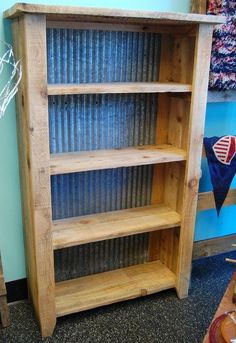 a wooden book shelf sitting on top of a carpeted floor next to a blue wall