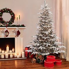 a decorated christmas tree sitting in front of a fire place with candles on the mantle