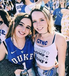 two young women posing for a photo in front of a crowd at a sporting event