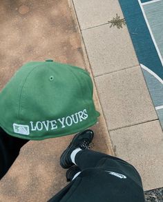 a person wearing a green hat and black pants standing next to a basketball court with the words love yours on it